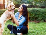 Woman training golden retriever dog performing obedience exercises in park